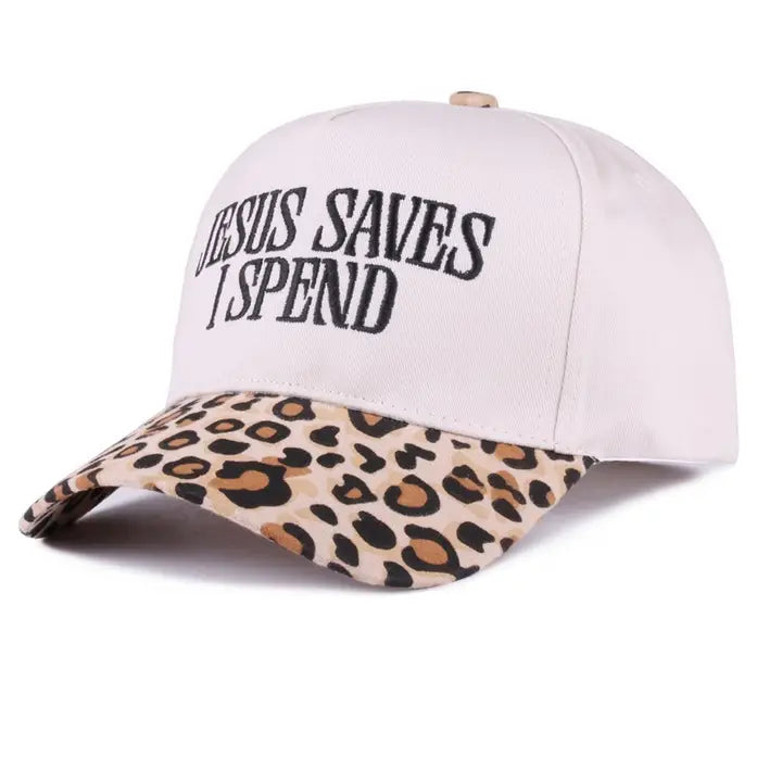 A baseball cap with a white crown and a leopard-print brim, featuring the text 'JESUS SAVES I SPEND' embroidered in black on the front.